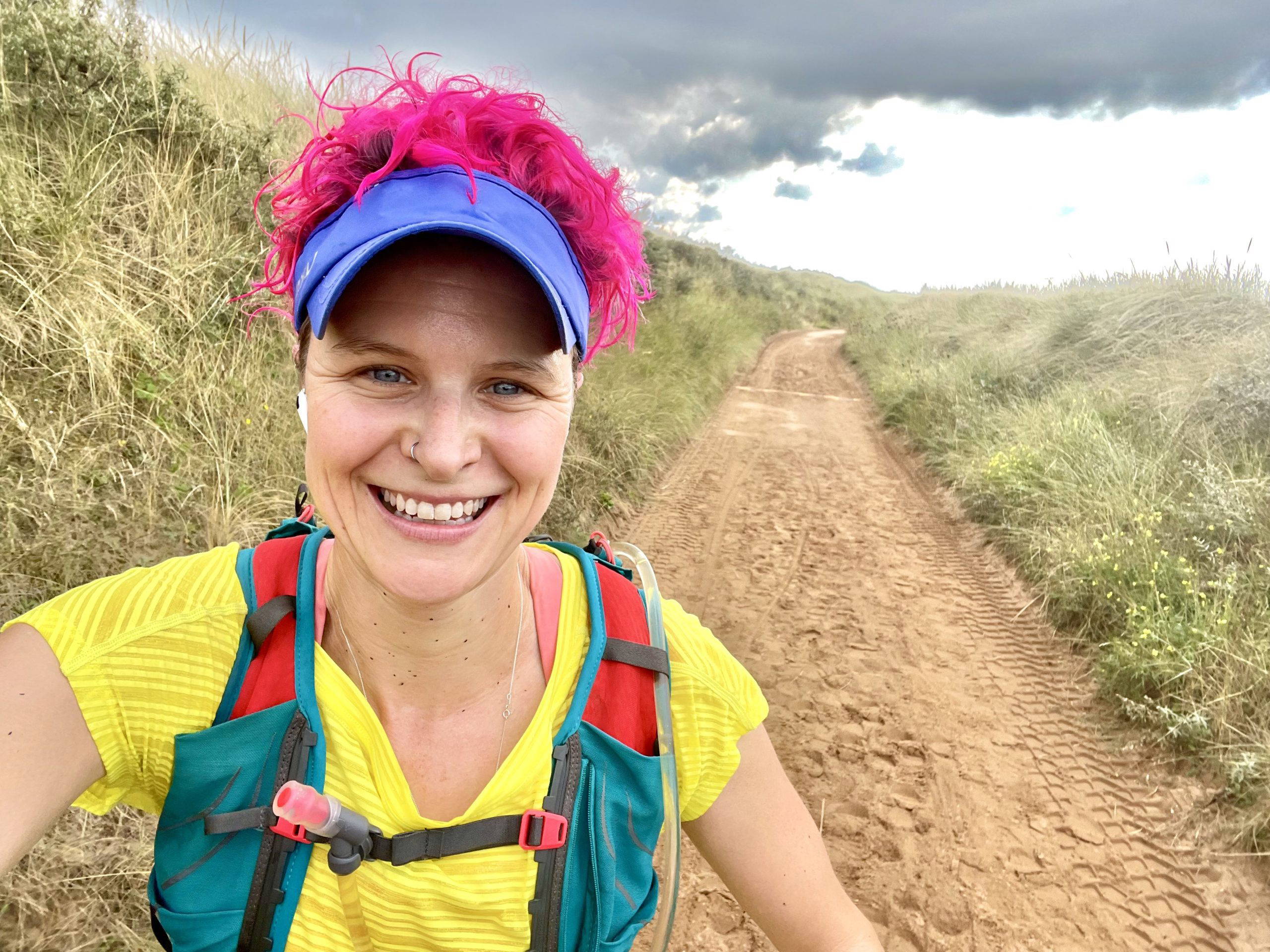 Anna McNuff, British endurance adventurer, author and speaker, smiling on a coastal trail run