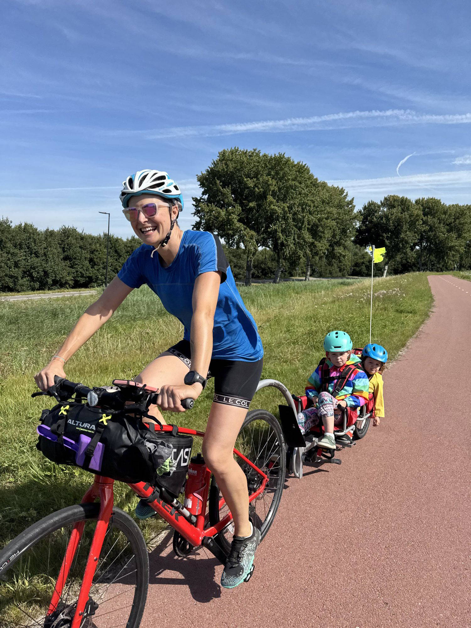 Anna McNuff cycling with her children in a bike trailer